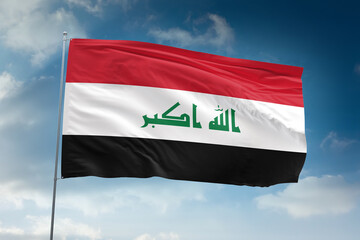 Realistic close-up of the Iraq flag waving on a tall flagpole under a bright sky with soft scattered clouds, showing smooth wind motion, vivid colors, and a clear, proud national atmosphere.
