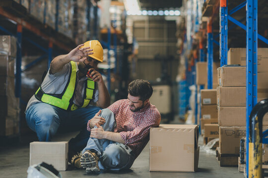 First aid support accident at work of worker at factory. Male worker has an accident on the floor in warehouse site