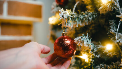 Hand caressing a red Christmas ball on a tree