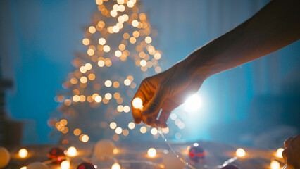 Hands of a boy arranging Christmas lights at night in front of the tree
