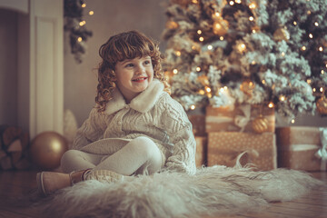 H&uuml;bsches kleines M&auml;dchen mit Locken sitzt vor einem Weihnachtsbaum l&auml;chend mit Weihnachtsdeko und Lichtern Bokeh, abendliche Stimmung Xmas, Var. 4
