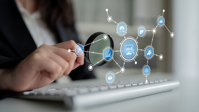 A business professional examines digital icons with a magnifying glass, showcasing the intersection of technology, analysis, and modern office activities. Tessel