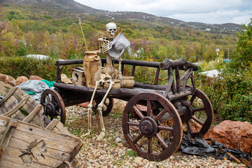 The skeleton of a man with a hat sits on a cart on a clear sunny day. Transportation recreation...