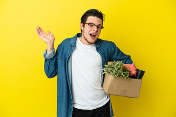 Russian Man making a move while picking up a box full of things isolated on yellow background...