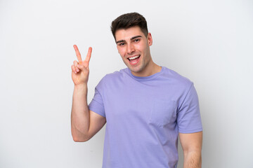Naklejka premium Young caucasian man isolated on white background smiling and showing victory sign