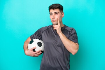 Young caucasian football player man isolated on blue background having doubts and thinking