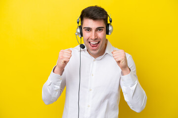 Telemarketer caucasian man working with a headset isolated on yellow background celebrating a...