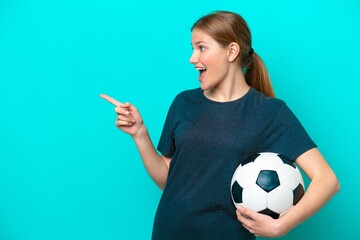 Young football player woman isolated on blue background pointing finger to the side and presenting...
