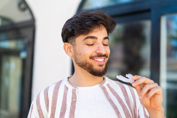 Handsome Arab man at outdoors holding invisible braces