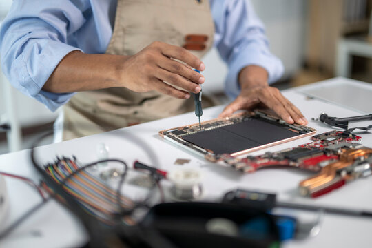 Technician repairing tablet computer using screwdriver on workbench