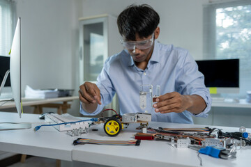 Robotics engineer assembling components of a robot prototype using a computer in the laboratory