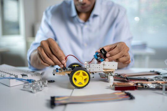 Engineer connecting wires to circuit board, building a robot prototype