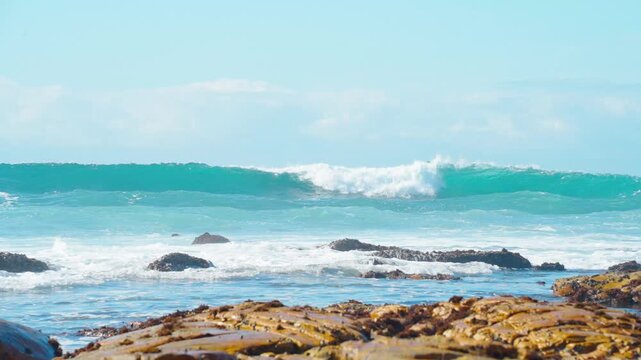 A series of slow-motion shots of beautiful blue waves rolling on the sea under the sunlight