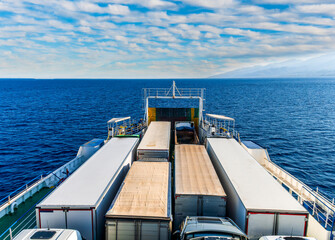 naval transport cargo ferry ship transporting wagon trucks to a destination port to supply trade goods to commercial sea port throuth sea and ocean