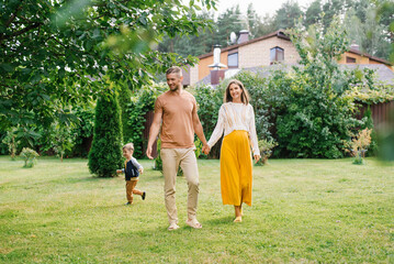 Obraz premium Pregnant Mother And Father Walking With Child In Garden