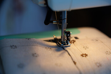 Creative sewing session with a sewing machine focused on a delicate patterned fabric in the evening light
