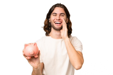 Young handsome man holding a piggybank over isolated background shouting with mouth wide open