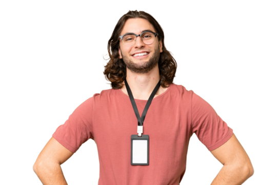 Young handsome man with ID card over isolated background posing with arms at hip and smiling