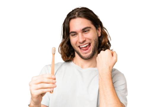 Young handsome man brushing teeth over isolated background celebrating a victory