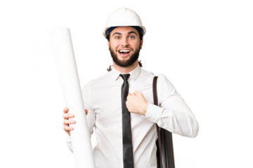Young architect man with helmet and holding blueprints over isolated chroma key background with surprise facial expression