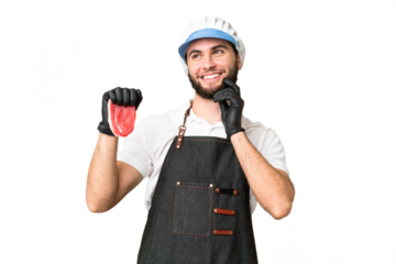 Butcher man wearing an apron and serving fresh cut meat over isolated chroma key background thinking an idea while looking up