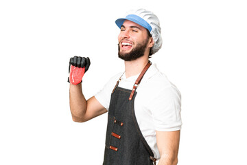 Butcher man wearing an apron and serving fresh cut meat over isolated chroma key background laughing in lateral position