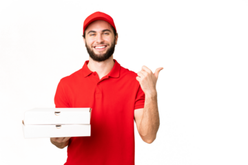 pizza delivery man with work uniform picking up pizza boxes over isolated chroma key background pointing to the side to present a product