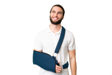 Young handsome man with broken arm and wearing a sling over isolated chroma key background thinking an idea while looking up