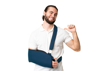 Fototapeta premium Young handsome man with broken arm and wearing a sling over isolated chroma key background proud and self-satisfied