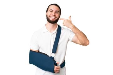 Young handsome man with broken arm and wearing a sling over isolated chroma key background giving a thumbs up gesture