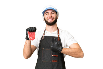 Butcher man wearing an apron and serving fresh cut meat over isolated chroma key background giving...