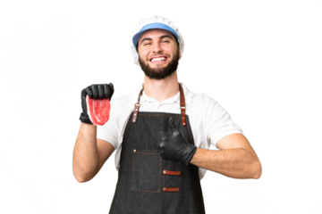 Butcher man wearing an apron and serving fresh cut meat over isolated chroma key background giving a thumbs up gesture