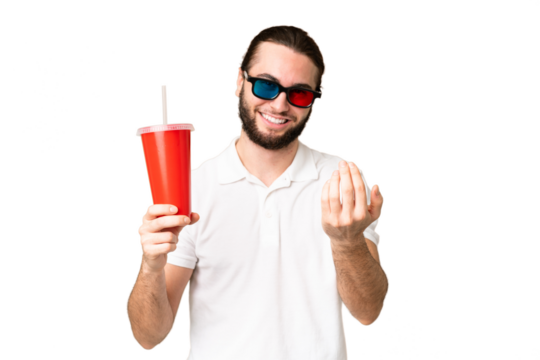 Young handsome man holding soda while watching a 3D movie over isolated chroma key background inviting to come with hand. Happy that you came