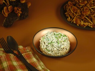 A creamy mushroom salad rests in a rustic bowl, garnished with fresh herbs. Nearby, sautéed mushrooms add to the warm, inviting atmosphere of a cozy dining setting