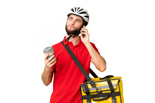 Young delivery man with thermal backpack over isolated chroma key background holding coffee to take away and a mobile