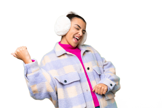 Young woman wearing winter muffs over isolated chroma key background making guitar gesture