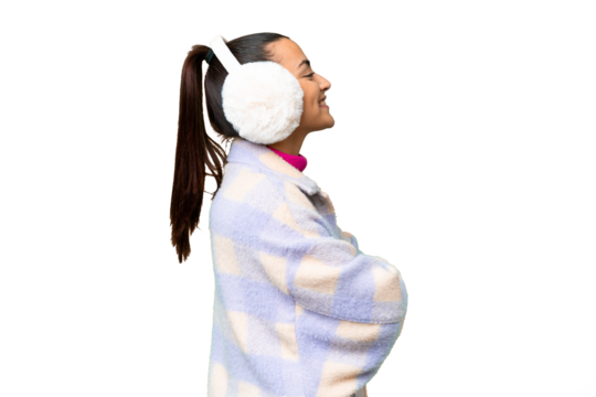 Young woman wearing winter muffs over isolated chroma key background in lateral position