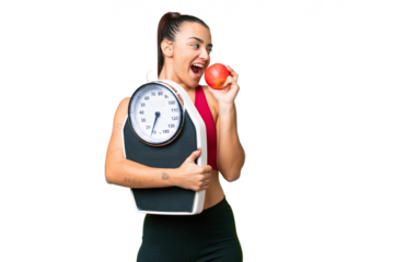Young beauty woman over isolated chroma key background with weighing machine and with an apple