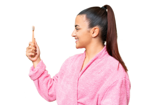 Young woman in a bathrobe brushing teeth over isolated chroma key background with happy expression