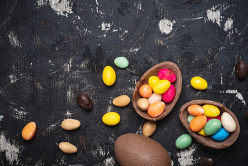 Chocolate Easter eggs on a wooden table with egg candies on a wooden table