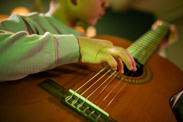 Child learning to play acoustic guitar strings