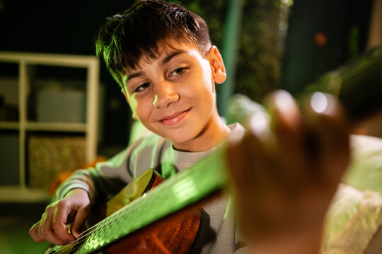 Young boy learning guitar playing music hobby