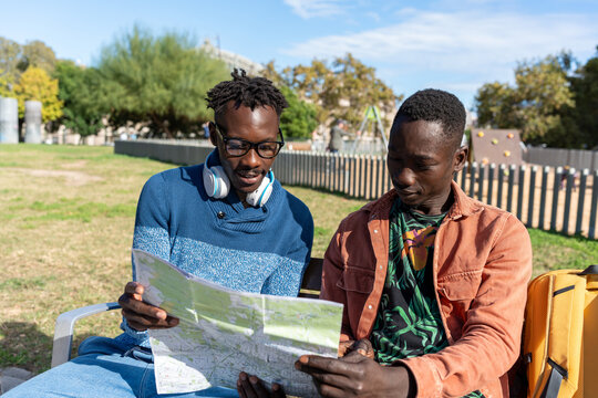Two African men planning their trip outdoors, closely reading a tourist map