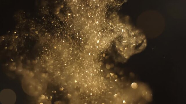 Delicate slow motion shower of shimmering gold bokeh particles gently falling and drifting within a shallow depth of field dark studio environment dust, sophisticated, peaceful