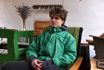 Young man with grimace expression sitting indoors