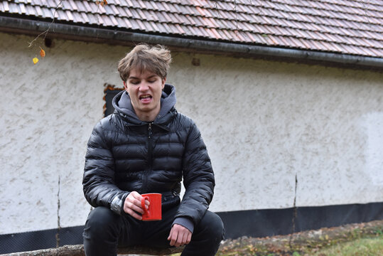 Young man makes a face with a red mug - Powered by Adobe