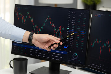 Cropped hand of businessman pointing to dynamic stock exchange data at red point by holding pen on computer screen in value rate online website program. Investor showing graph point on time. Infobahn.