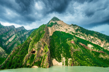 Picturesque view of a beautiful rocky mountain with a cave and a mountain lake at the base. North Caucasus