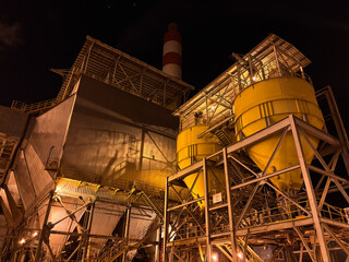 A sprawling industrial complex brightly illuminated against the dark night sky, showcasing modern manufacturing and energy production