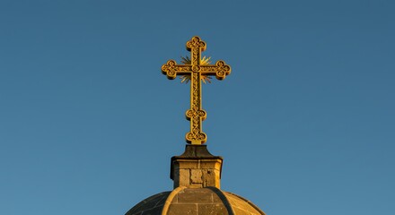 Ornate golden cross atop stone dome against a clear, gradient blue sky
